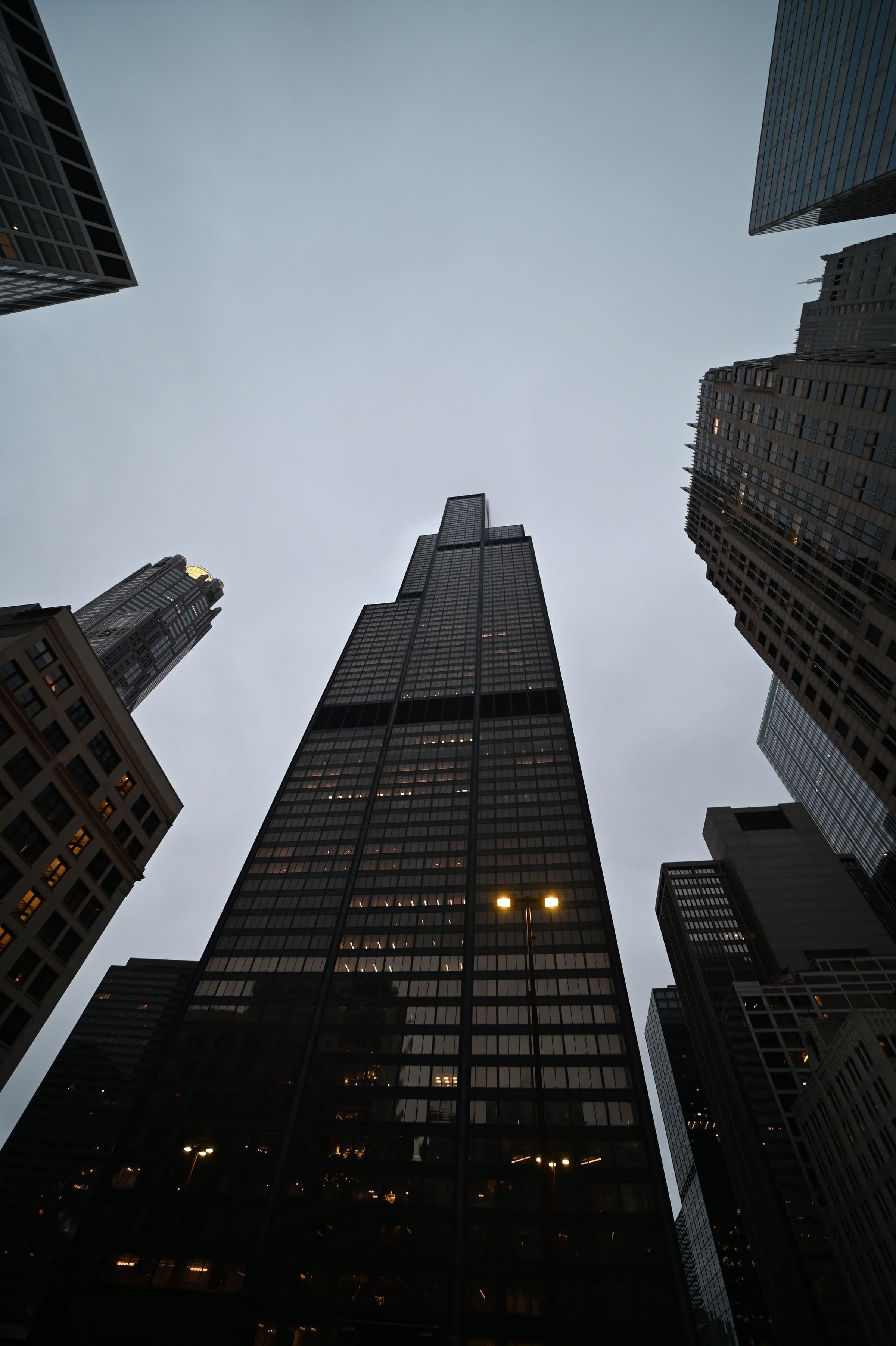 Financial-district towers at dusk, seen from the street canyon.
