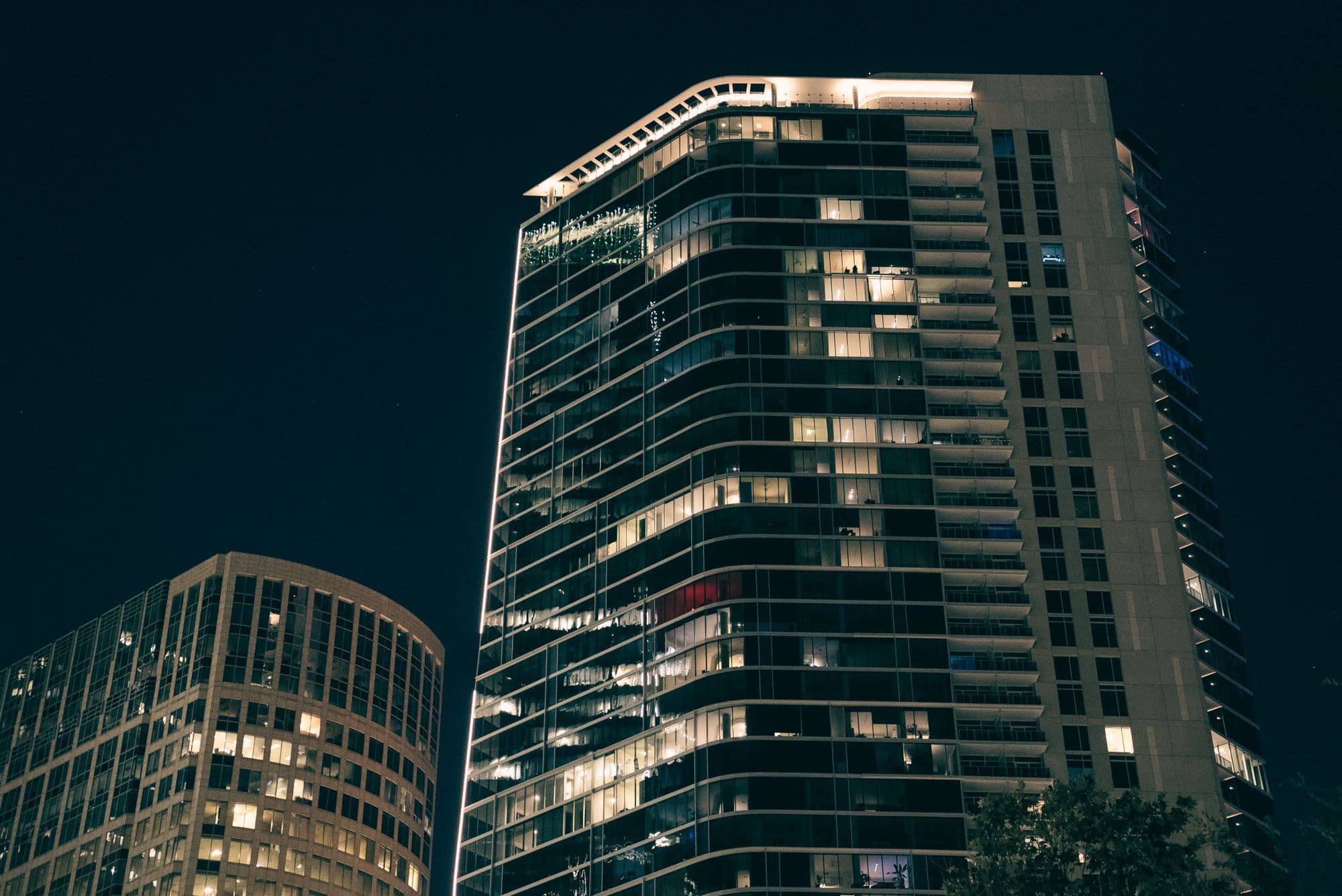 Modern glass-and-steel towers illuminated at night.